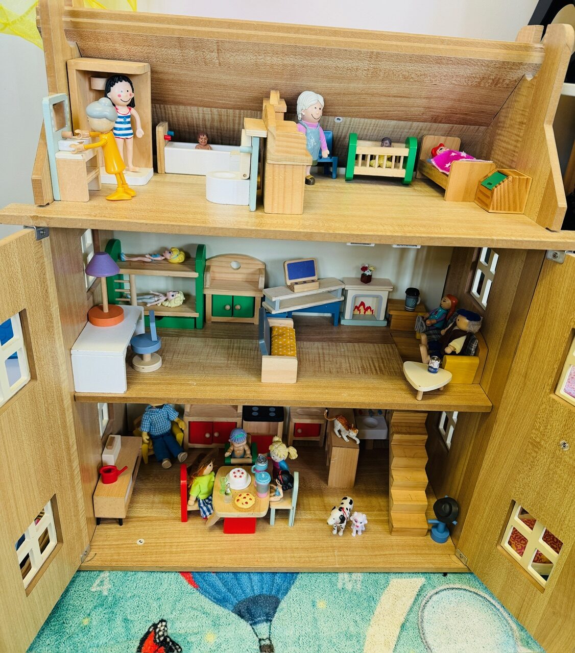A wooden three-storey dolls' house, furnished room by room